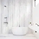 ALUCOM® Design Travertin Weiß – Wandverkleidung in modernem Badezimmer mit freistehender Badewanne.